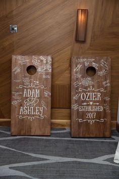 two wooden signs with names on them sitting in front of a wall and carpeted floor