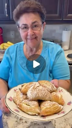 a woman sitting at a table with a plate of croissants