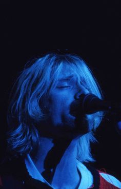 a man with long hair singing into a microphone