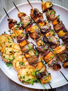 a plate with skewered meat and vegetables on it