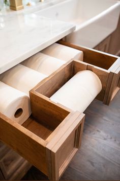 an open drawer with rolls of toilet paper in it and a marble counter top behind it