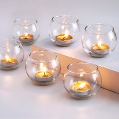 four clear glass bowls with lit candles in them