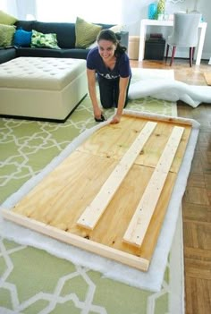 a woman laying on top of a wooden floor next to a white couch and green rug