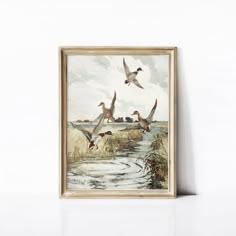 three ducks flying over a body of water in front of a painting on the wall