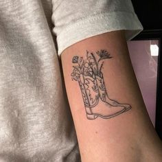 a tattoo on the arm of a woman with boots and flowers