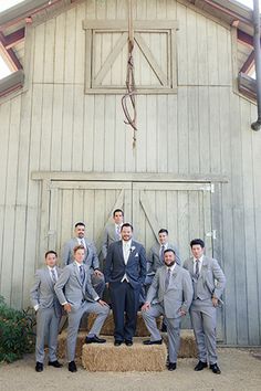 a group of men standing next to each other in front of a barn