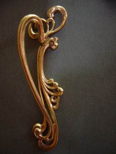 an ornate gold metal hook on a black surface with the word love written in it