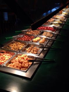 a buffet table filled with lots of different types of food on trays next to each other