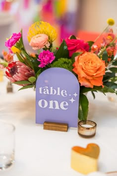 the table is set with colorful flowers and place card holders for guests to use on their wedding day