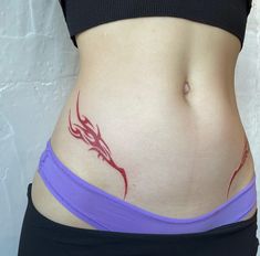 a woman's stomach with a red tattoo on the side and purple band around her waist