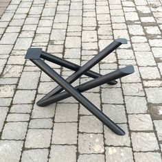 a black metal object sitting on top of a brick floor next to a sidewalk with cobblestones