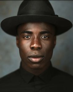 a man in a black shirt and hat is looking at the camera with an intense look on his face