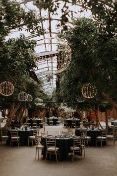 tables and chairs are set up in the middle of an indoor venue with lights hanging from the ceiling