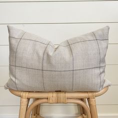 a cushion sitting on top of a wooden stool next to a white and gray wall