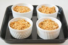 four small cups filled with food on top of a black tray