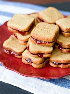 a red plate topped with cookies covered in jelly filling on top of a blue and white table cloth