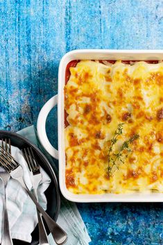 a casserole dish with meat and cheese in it on a blue tablecloth