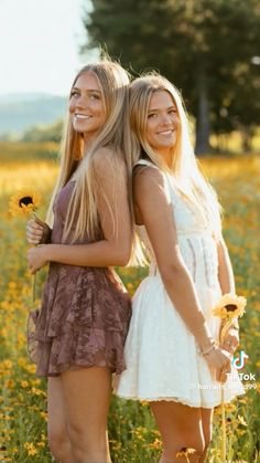 two beautiful young women standing next to each other in a field full of yellow flowers