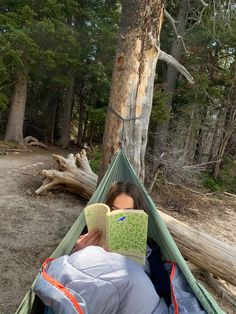 a woman reading a book while laying in a hammock with a map on it