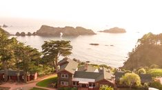 an aerial view of a house on the coast with trees and water in the background