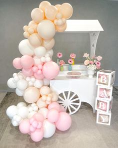 a table topped with lots of balloons next to a white cart filled with pink and white flowers