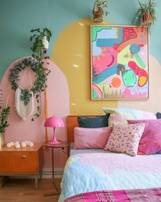 a bedroom with pink, blue and yellow decor on the walls is pictured in this image