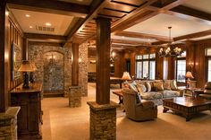 a living room filled with furniture next to a stone wall and ceiling mounted chandelier