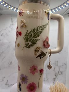 a glass mug with flowers and leaves on it