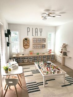 a playroom with toys and storage bins on the wall next to a table