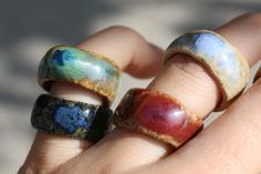 a person's hand holding three rings with different colors and shapes on them,