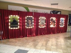 a room with red curtains and pictures on the wall next to chairs in front of them