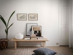 a living room with white walls and wooden flooring, two framed pictures on the wall