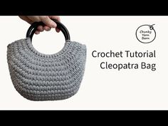 the crochet purse is being held by a person's hand with an oval handle