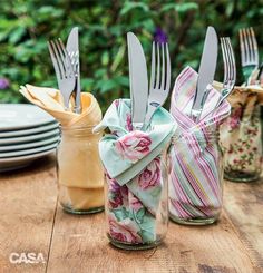 four mason jars with forks and napkins in them