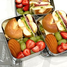 four tins filled with sandwiches and fruit