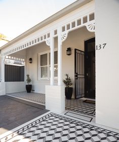 a white house with black and white tiles on the front door, porch and entryway