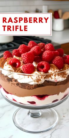 a raspberry trifle in a glass dish on a marble counter top with the words raspberry trifle above it