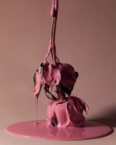 a pink vase with flowers on top of it and dripping paint all over the base