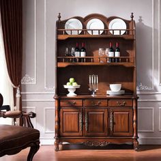 an old wooden china cabinet with wine glasses on it's top shelf and dishes in front of it