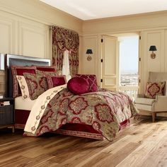 a large bed with red and gold comforter in a bedroom next to a window