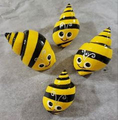 four yellow and black ceramic bees with faces painted on them, all lined up in a circle