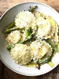 a white bowl filled with mashed potatoes and asparagus on top of a wooden table