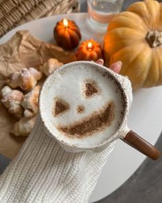 a person holding a coffee cup with a smiley face drawn in the foam on it