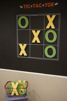 a tic tac toe board on the wall next to a basket with letters