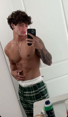 a shirtless man taking a selfie in front of a mirror with his cell phone