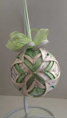 an ornament with green and white designs on it sitting on a wire stand