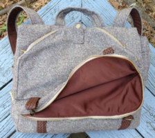 a gray and brown bag sitting on top of a wooden table next to a tree