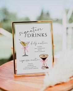 a sign that is sitting on top of a table with some wine glasses and feathers