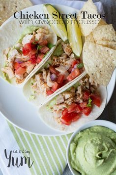 chicken street tacos with avocado and salsa on a plate next to chips