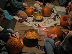 people sitting on the floor carving pumpkins for halloween